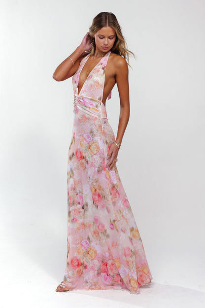 Side profile of a women's elegant pink floral halter maxi dress with a flowing skirt and deep V-neck.