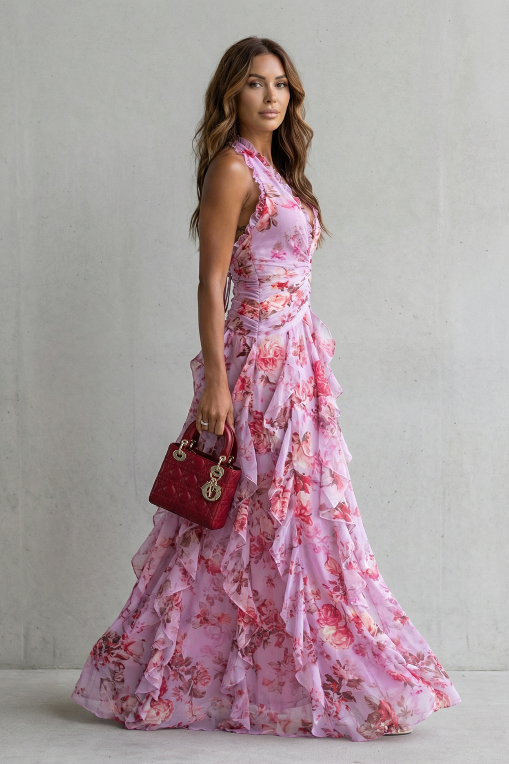 Side profile of a woman in a flowy purple floral maxi dress featuring a halter neckline and ruffled skirt.