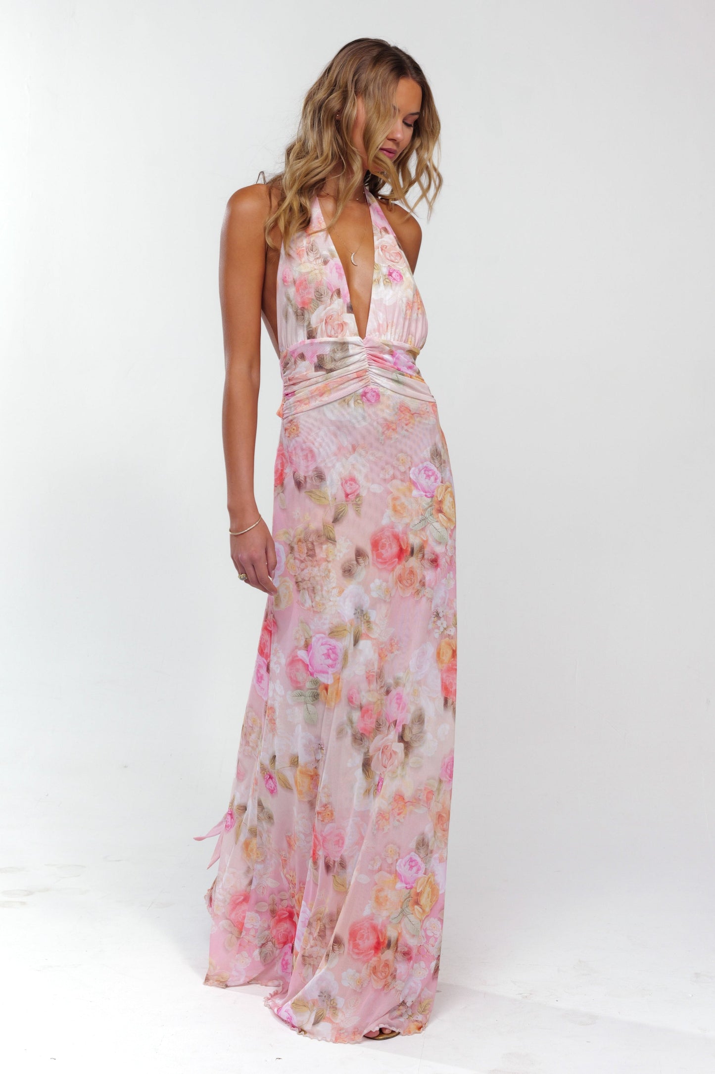 Women's pink floral halter maxi dress with a ruched bodice and long, flowing skirt, perfect for wedding guests.