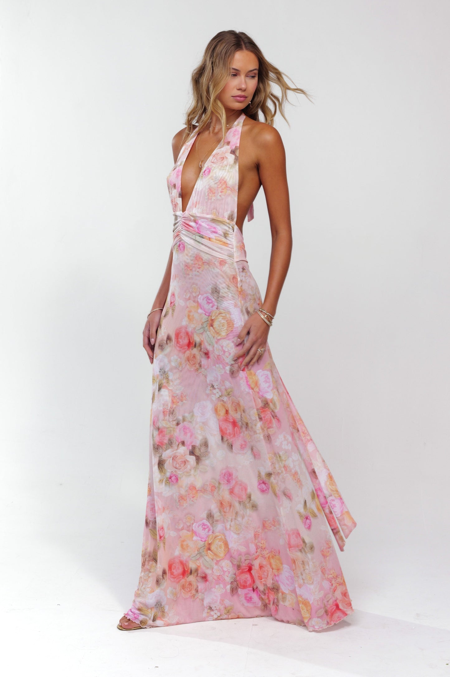 Dynamic side view of a women's pink floral halter maxi dress, showing the full length and elegant flow.