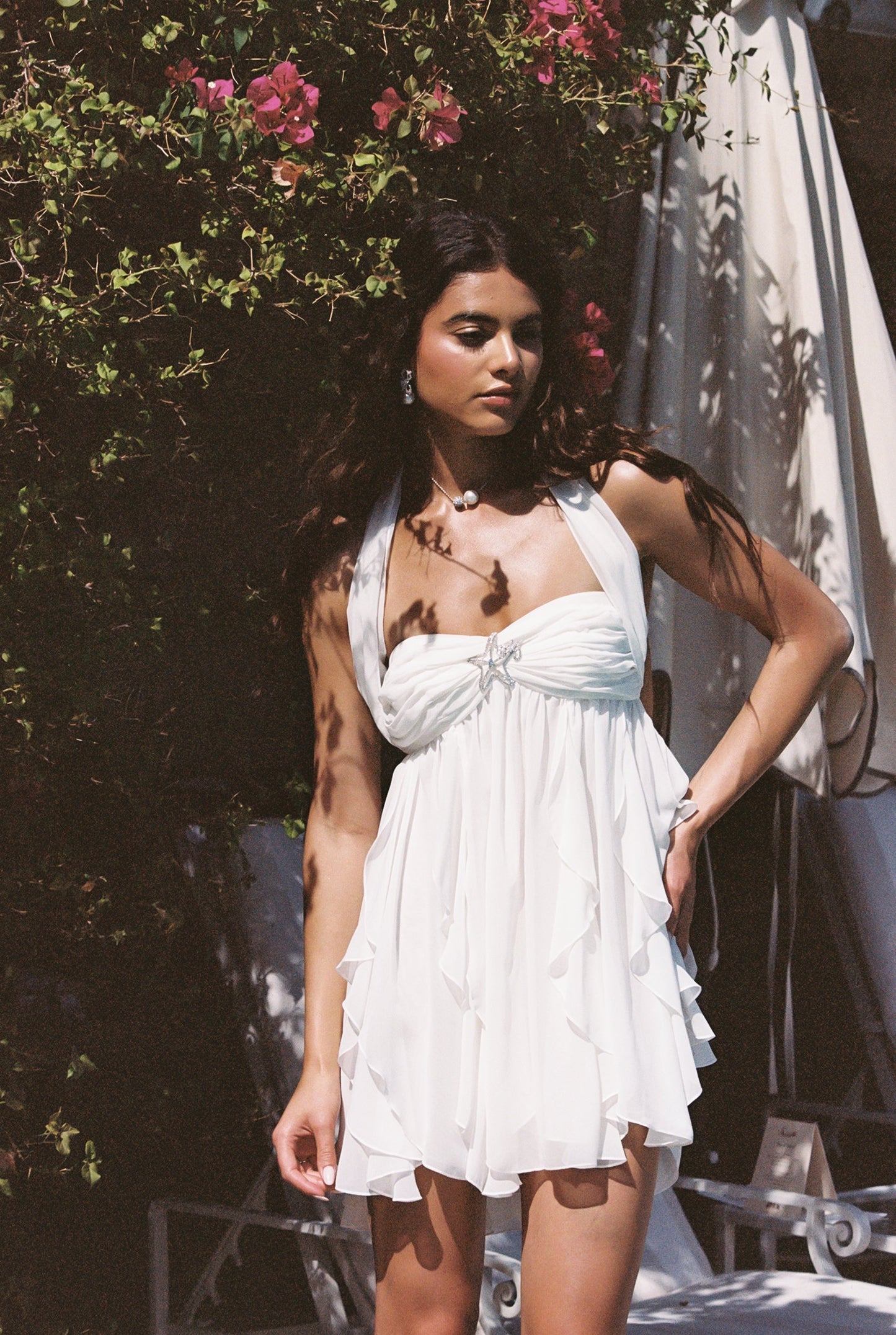 White halter neck mini dress with ruffled tiered skirt and star embellishment, perfect for vacation outfits.