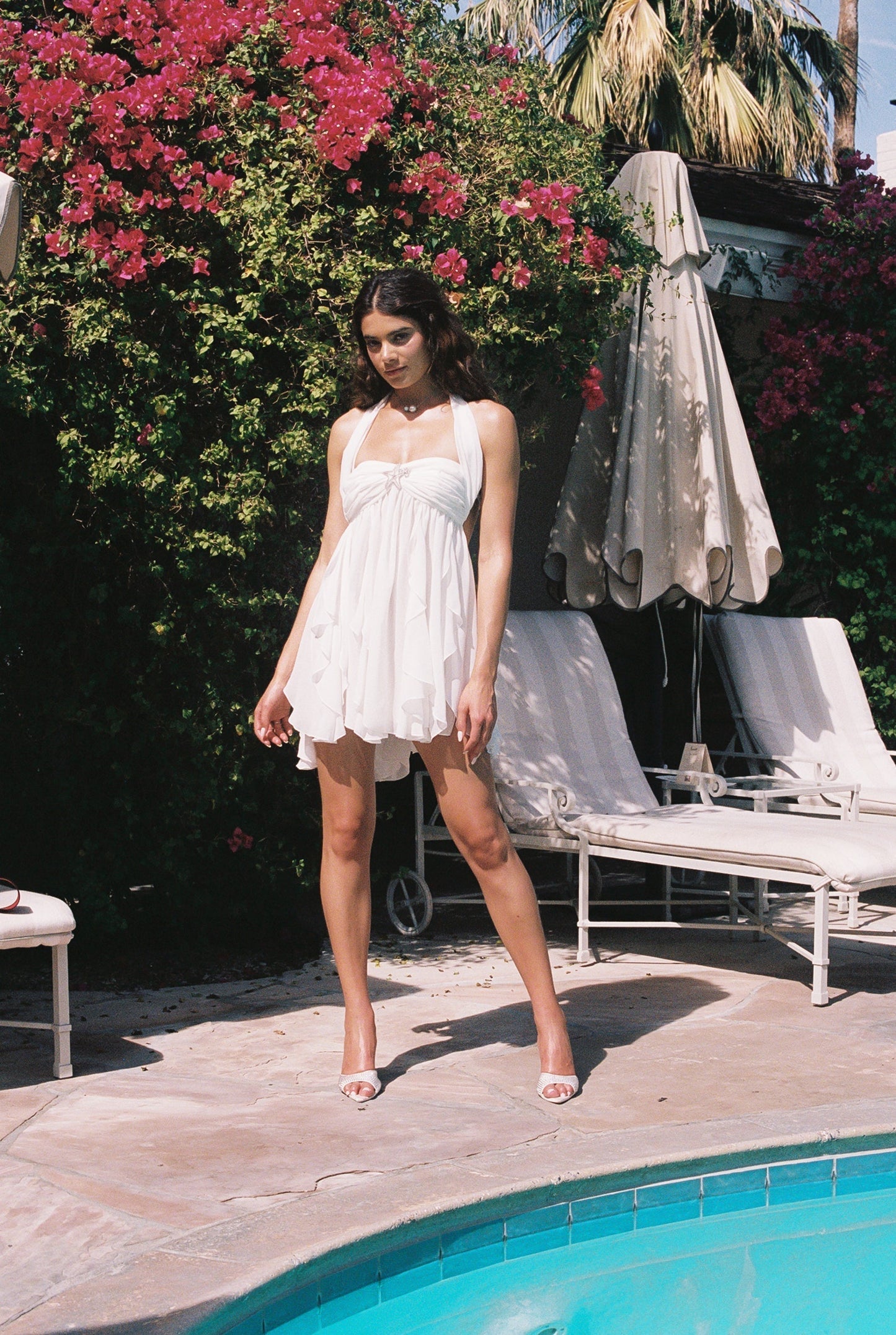 Full body view of a white halter neck mini dress with a tiered ruffled skirt, ideal for a beach dress.