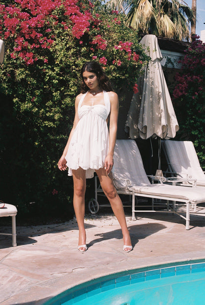 Full body view of a white halter neck mini dress with a tiered ruffled skirt, ideal for a beach dress.
