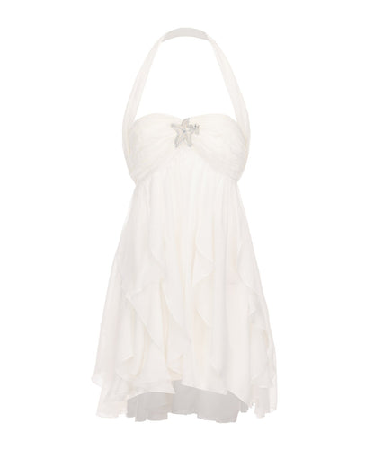 Front view of a white halter neck mini dress with a ruched bodice and a silver star charm, featuring a tiered skirt.