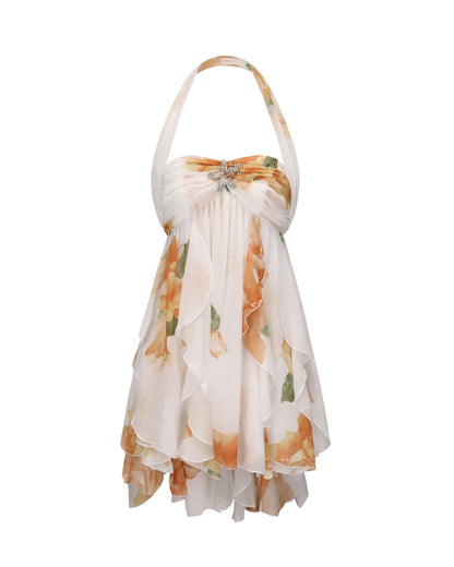 Studio shot of women's floral halter neck tiered mini dress with white base, orange and brown floral print, and a star brooch.