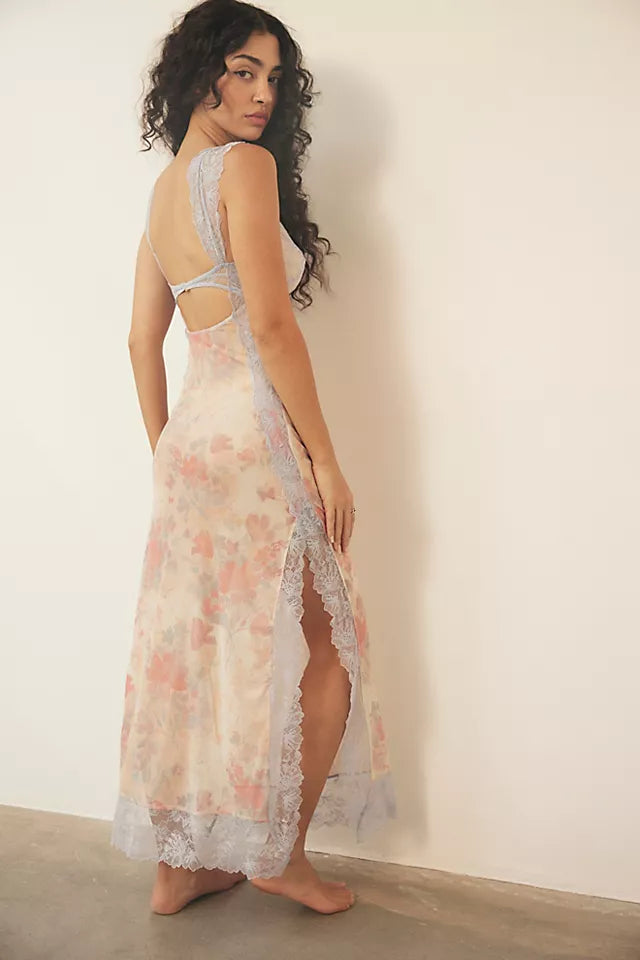 Back view of a light peach floral lace cut out back maxi dress with subtle pink and orange flowers, featuring side slits.