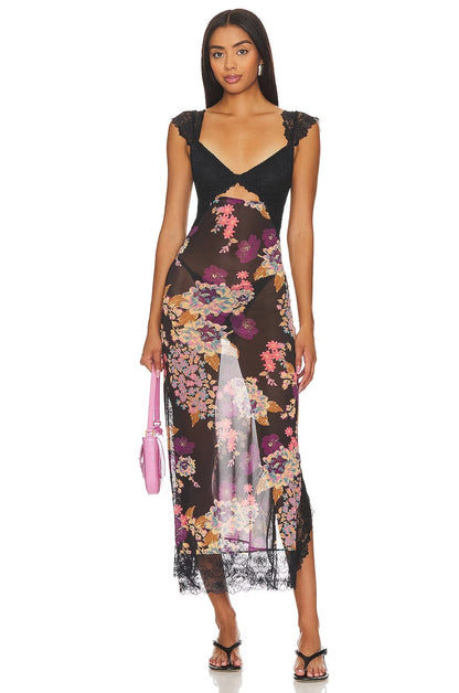 Front view of a women's black floral lace cut out back maxi dress with a colorful floral print and a pink handbag, perfect for a wedding guest dress.