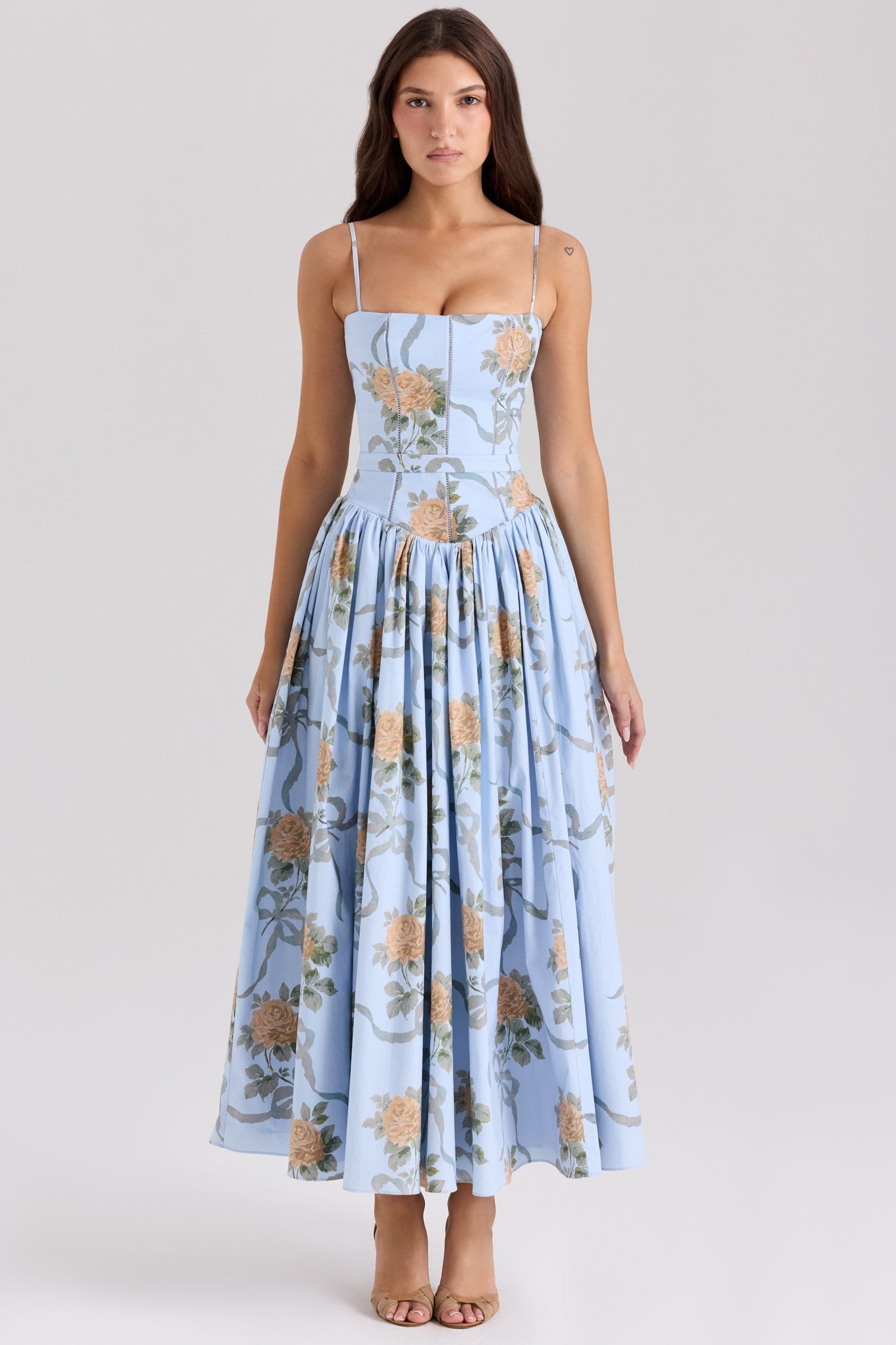 Front view of a light blue floral printed square neck midi dress with thin straps, featuring yellow roses and green ribbon details, perfect for vacation outfits.