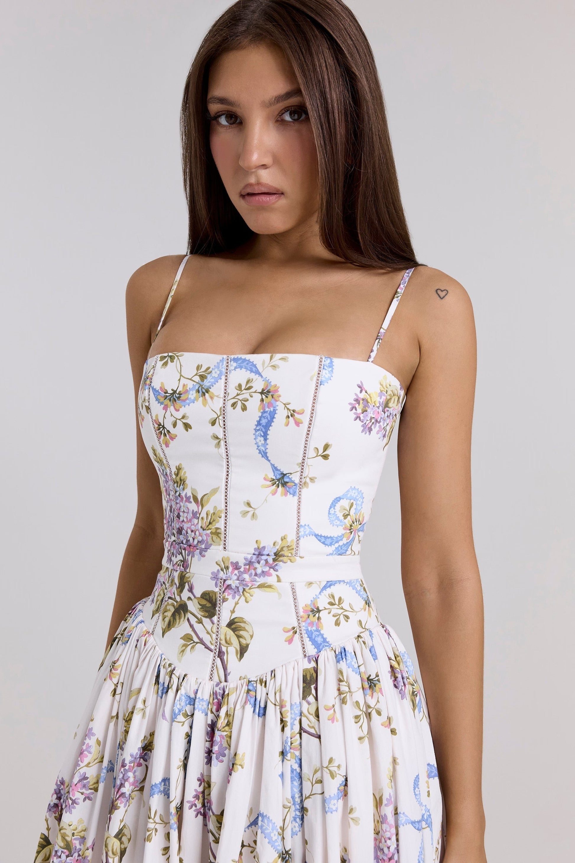Close-up of the bodice on a white floral square neck midi dress, showing purple and blue ribbon pattern details.