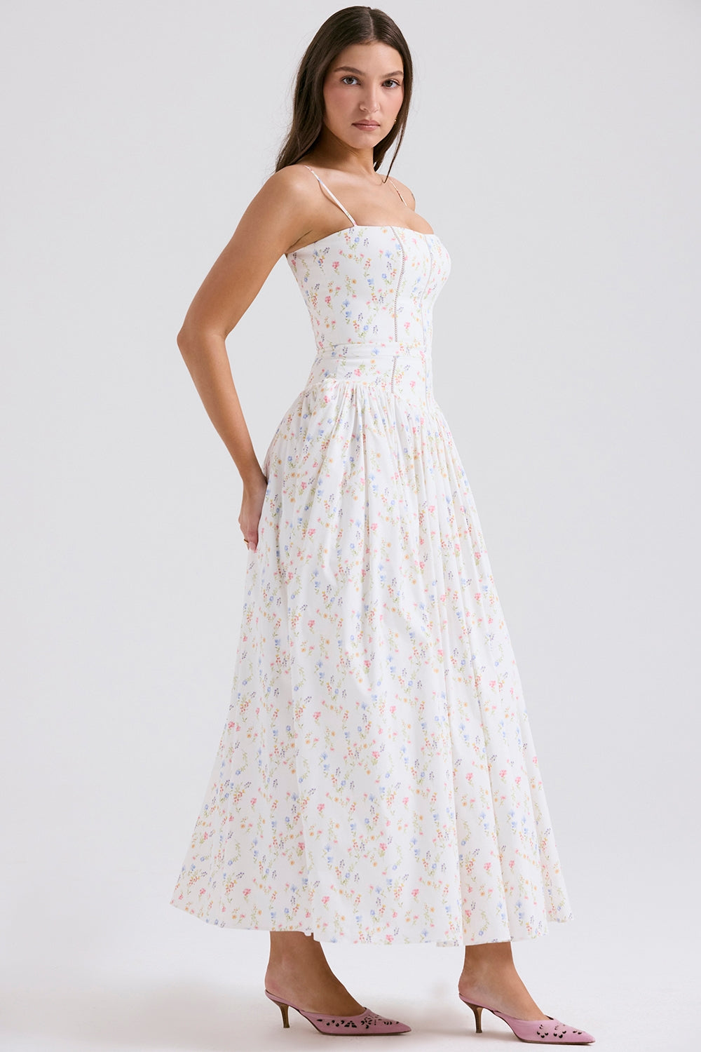 Side view of a white midi dress with a subtle multi-color floral pattern, square neck, and a cinched waist.