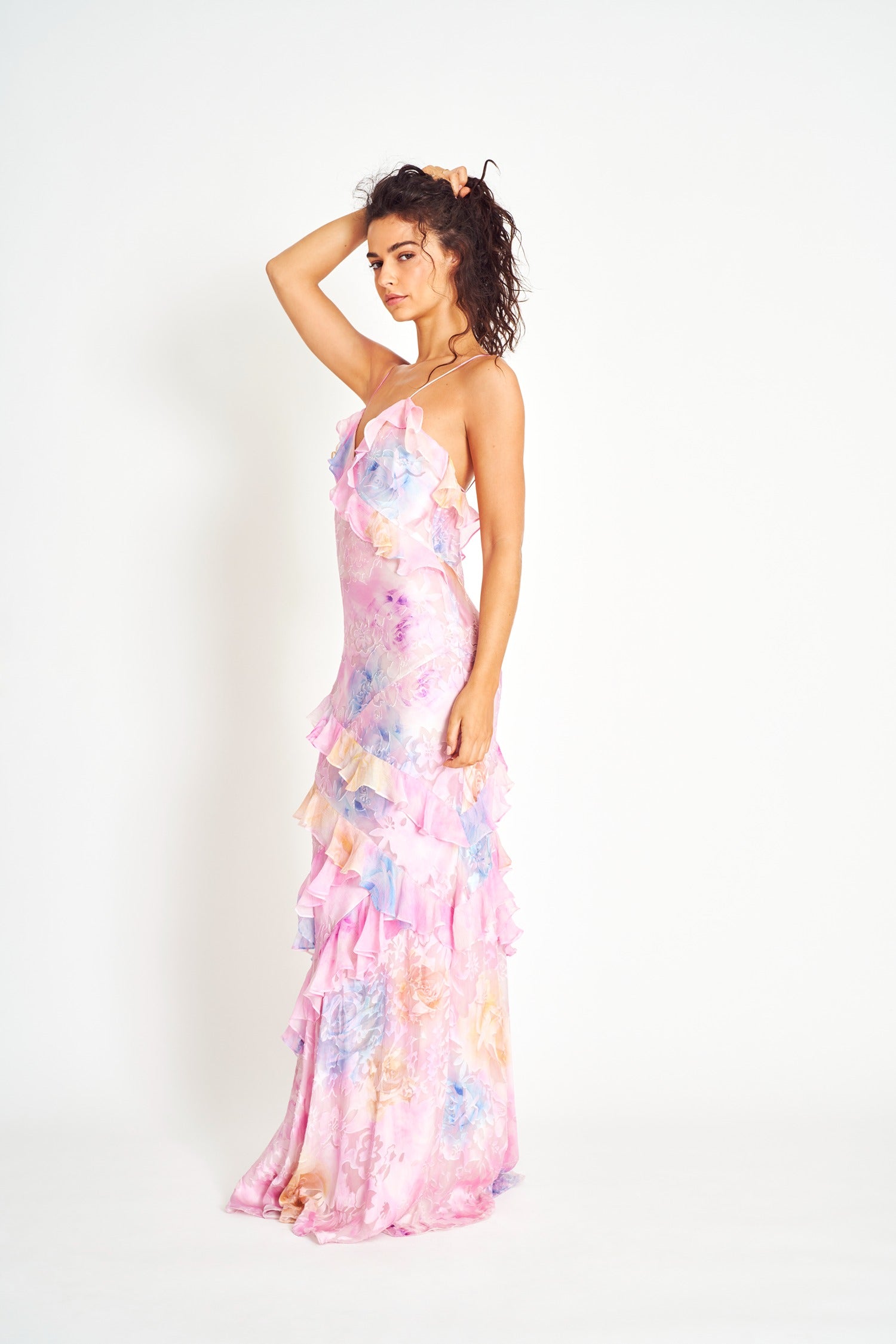 Side profile of a women's floral ruffle strap maxi dress in pink, highlighting the elegant silhouette and flowing ruffles from top to bottom.