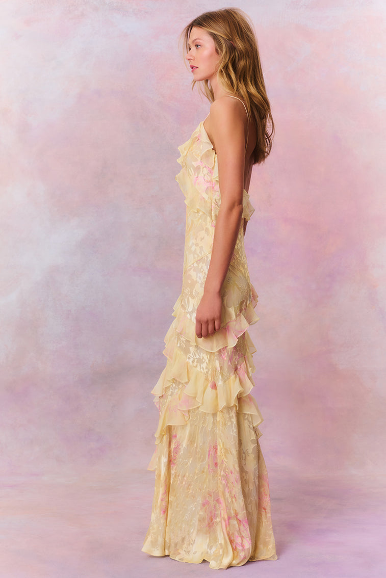 Side profile of the light yellow floral ruffle strap maxi dress, highlighting the flowing silhouette and ruffle details.