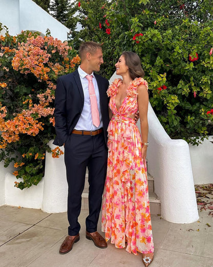Couple looking at each other, woman in a summer floral V-neck maxi dress in orange and pink, with ruffled shoulders.