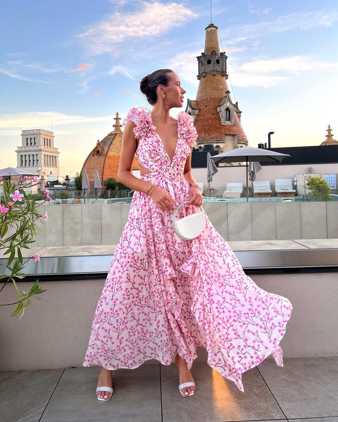 Women's summer floral V-neck maxi dress in light pink with white floral print, ruffled shoulders and waist cutouts, flowing in the breeze.