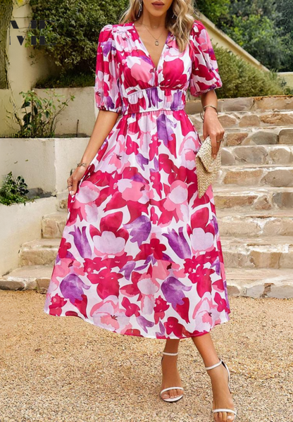 Women's pink and purple floral v-neck midi dress with short sleeves, cinched waist, and a full skirt, great for a midi wedding guest dress.