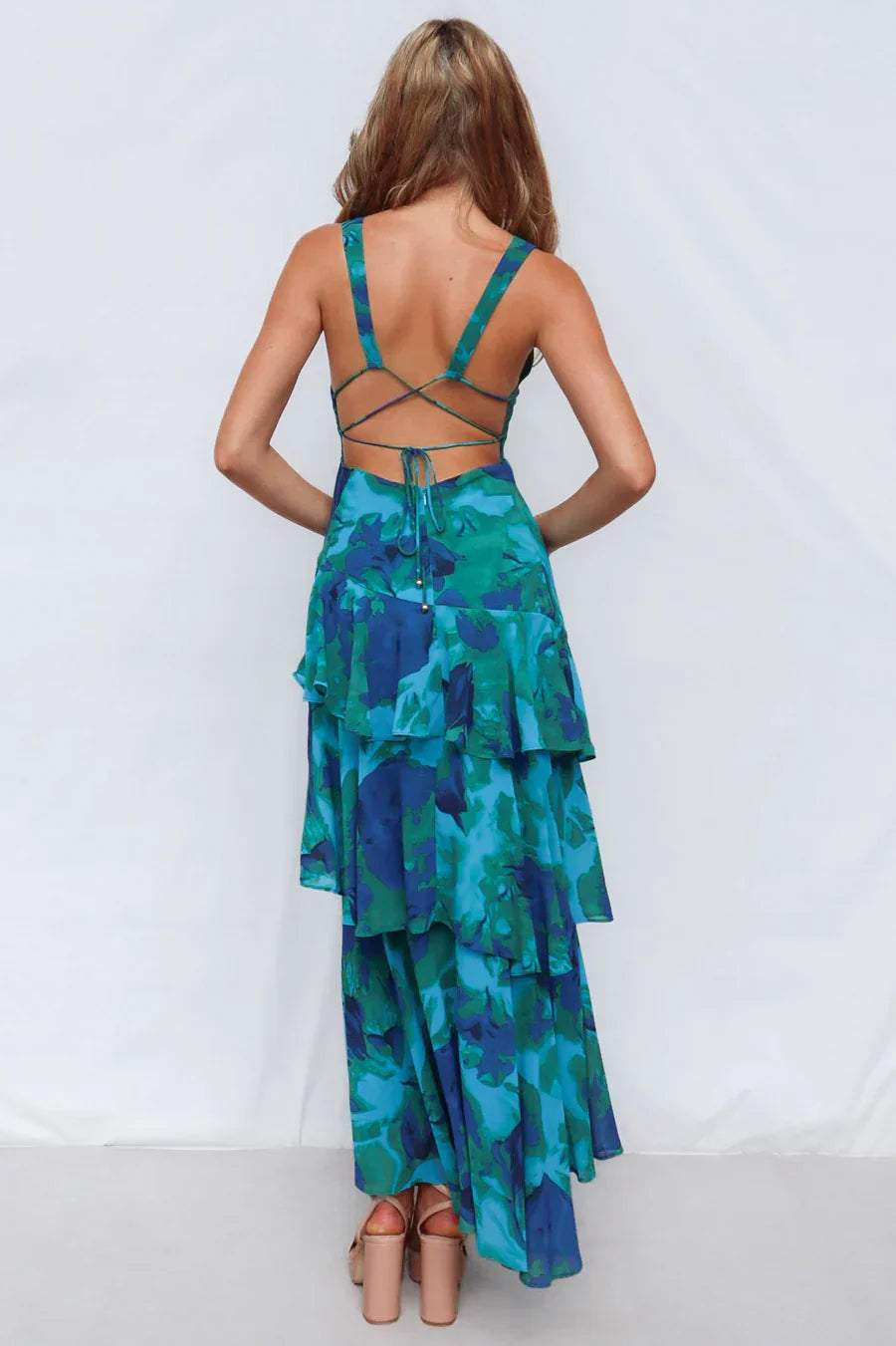 Back view of a women's blue floral V-neck tiered maxi dress, displaying the criss-cross back straps and tiered skirt.
