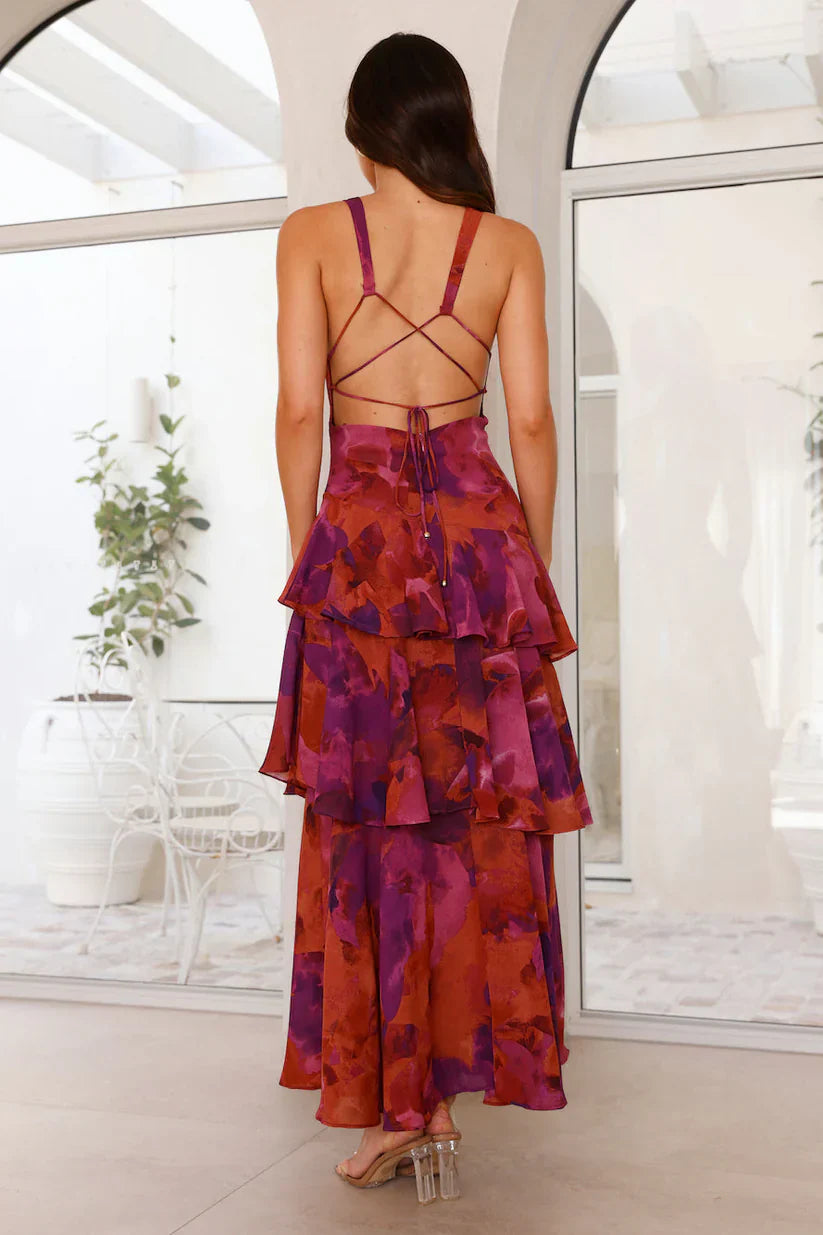Back view of a women's red and purple floral V-neck tiered maxi dress, showing the criss-cross back and tiered design.
