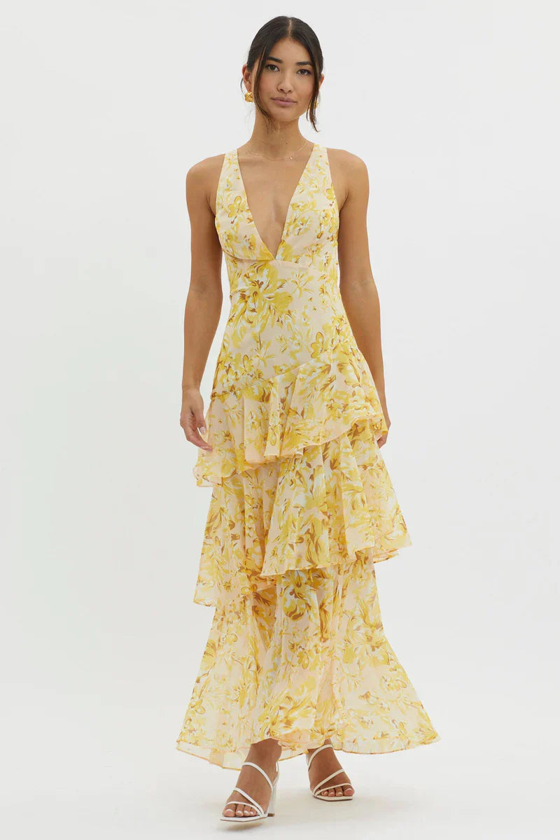 Full-length view of a women's floral v-neck tiered maxi dress in yellow, featuring a deep v-neckline and flowy skirt with ruffles.