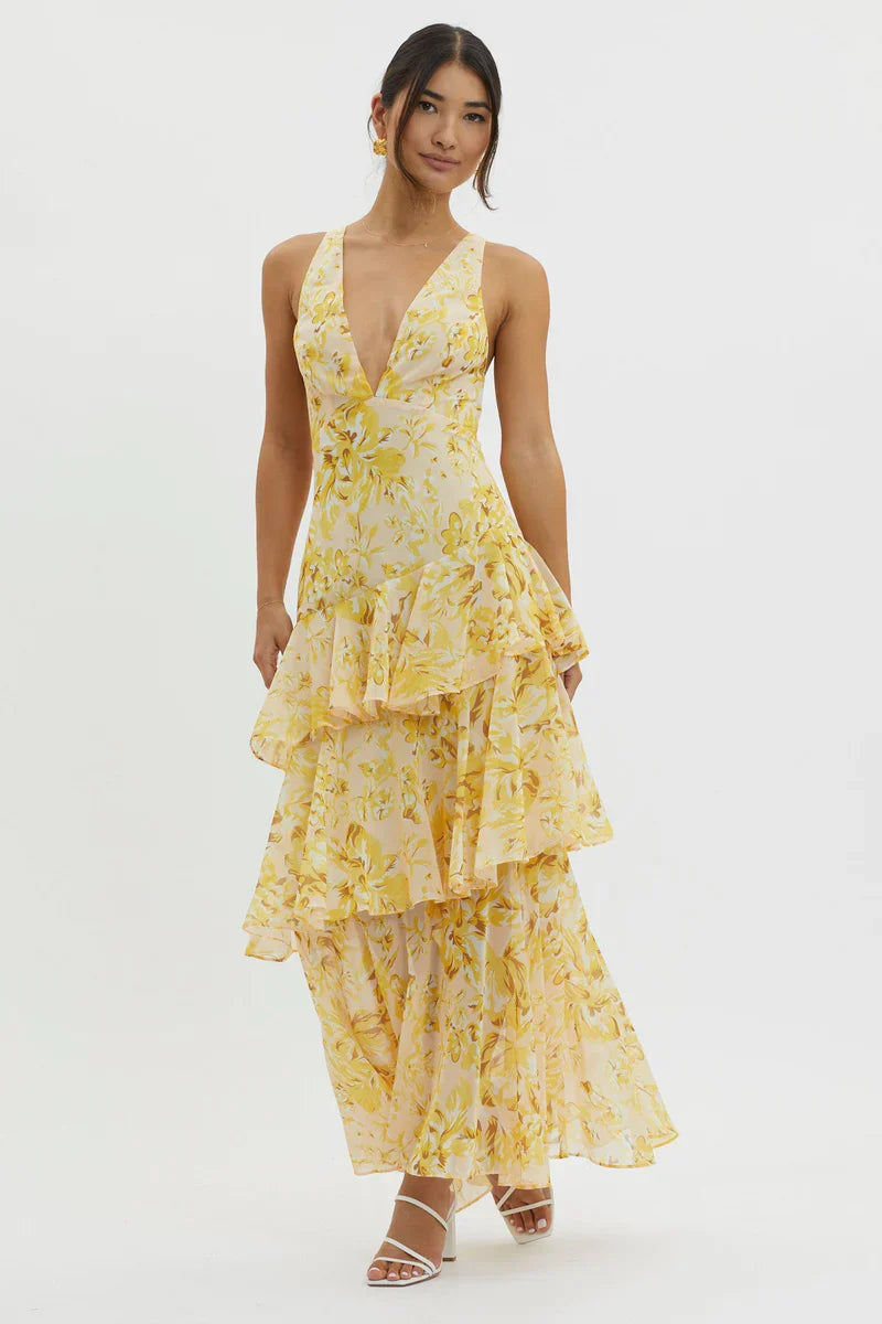 Side profile of a women's yellow floral v-neck tiered maxi dress, highlighting the elegant drape and layered skirt design.