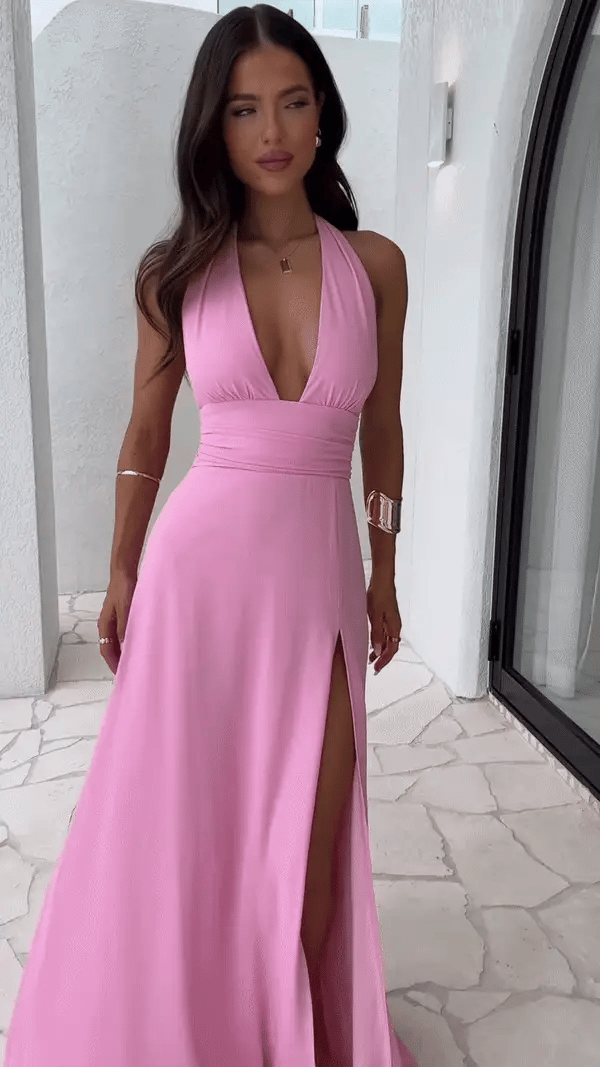 Pink halter neck maxi dress in soft drape fabric with side slit, front view in shaded light
