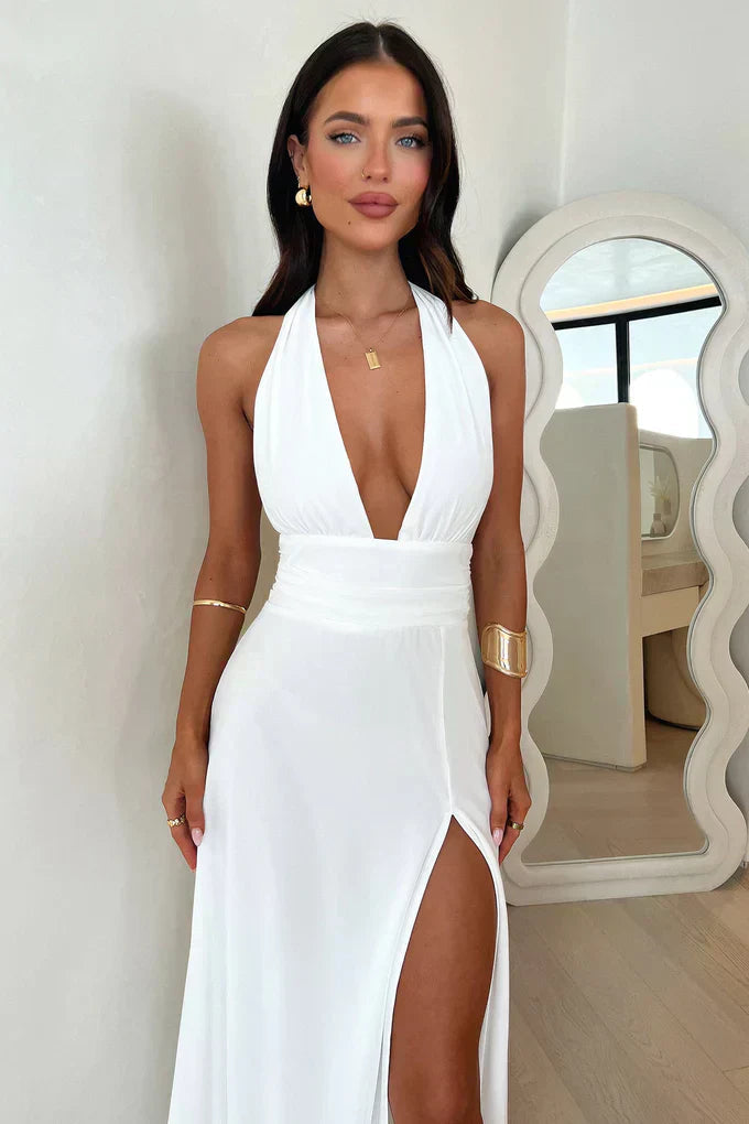 Front close view of white halter neck maxi dress showing deep V bodice, fitted waist and side slit
