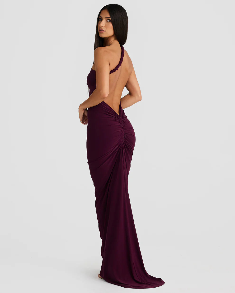 Plum bodycon maxi dress side view with open back detail, ruched hip, and long train