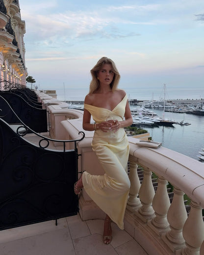 Front view of a woman posing in a light yellow off-shoulder satin maxi dress, ideal for wedding guests.