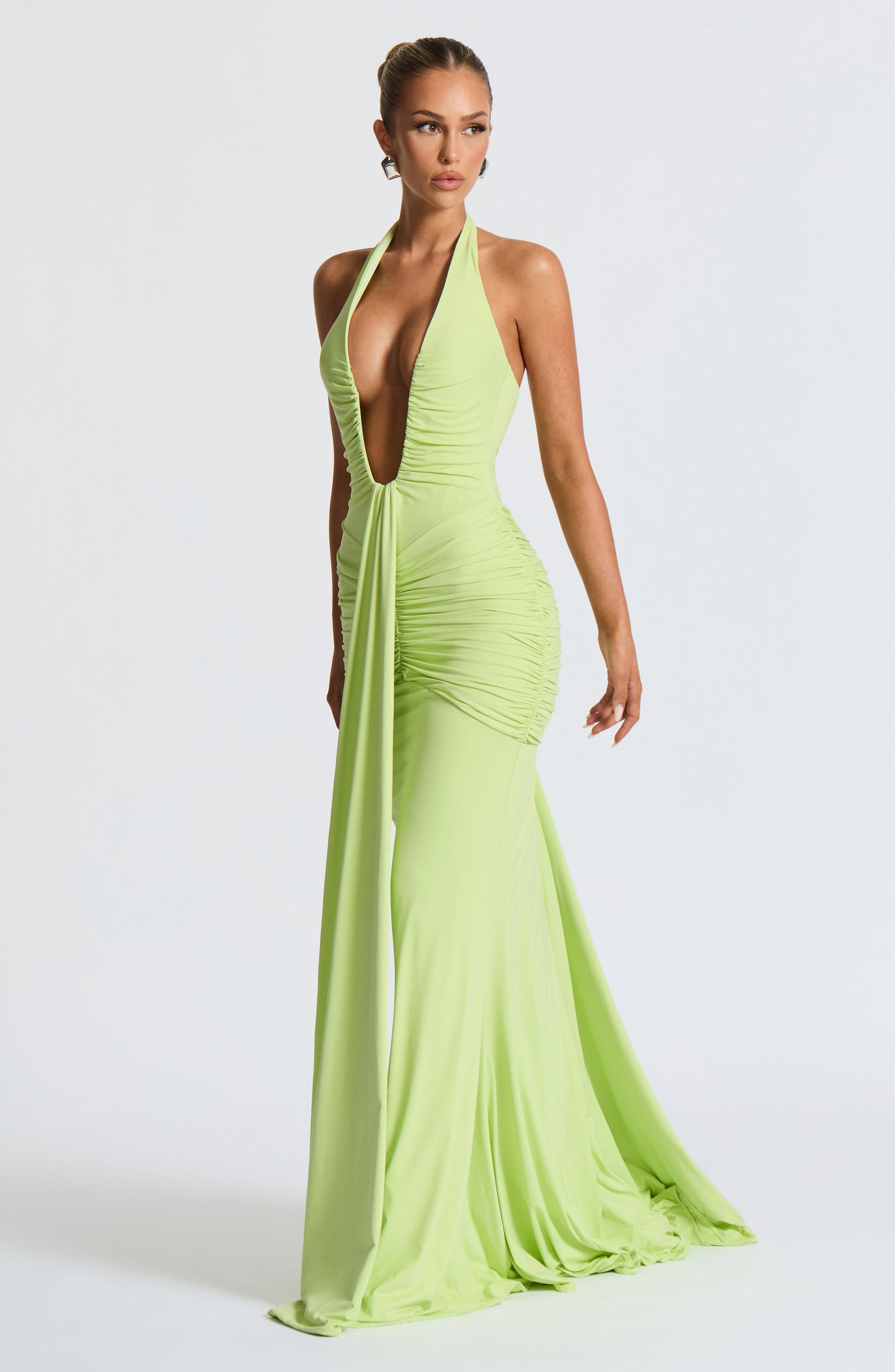 Side angle lime green plunge halter bodycon maxi dress showing ruched side panel and flowing train