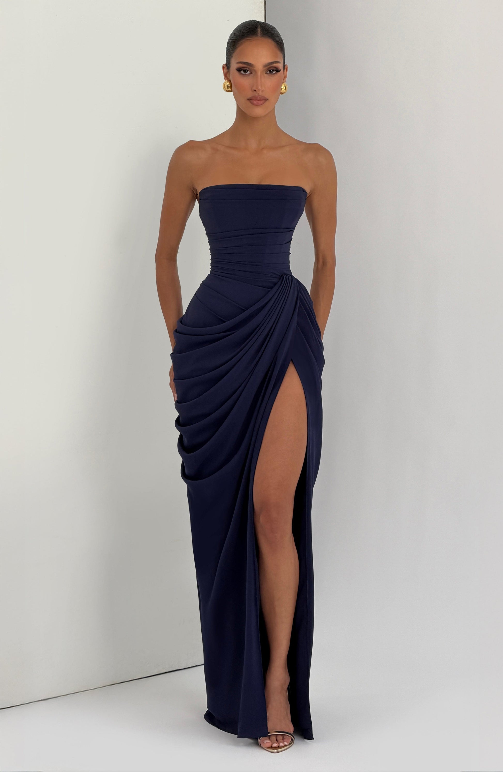 Full-length navy strapless formal maxi dress with side draping and thigh-high slit front view
