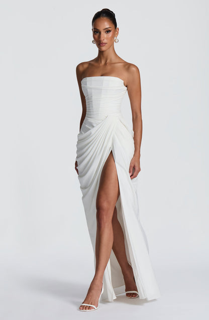 White strapless maxi dress angled view showing pleated drape at hip and high slit, bodycon style
