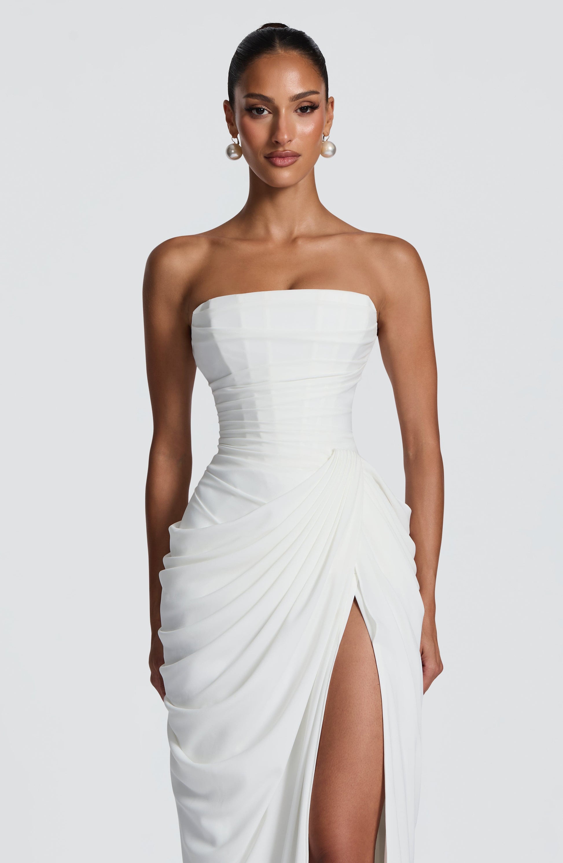 White strapless ruched bodice maxi dress close-up with draped overlay and slit detail