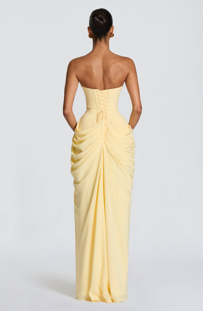 Back view of pale yellow strapless maxi dress with corset lace-up detail and gathered draped skirt