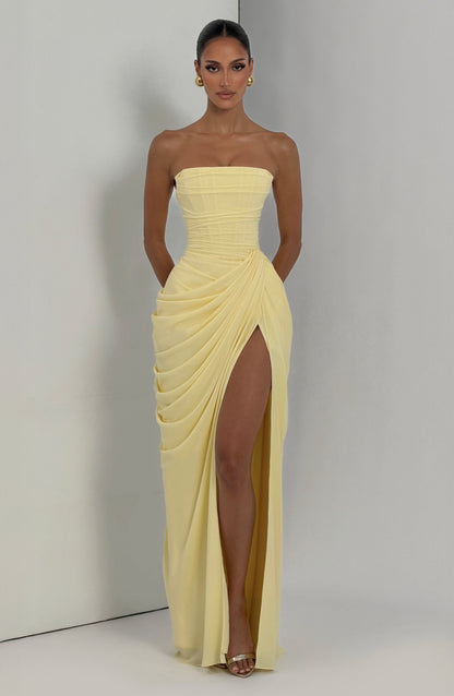 Pale yellow strapless draped maxi dress in natural lighting, showing fitted bodice and thigh slit