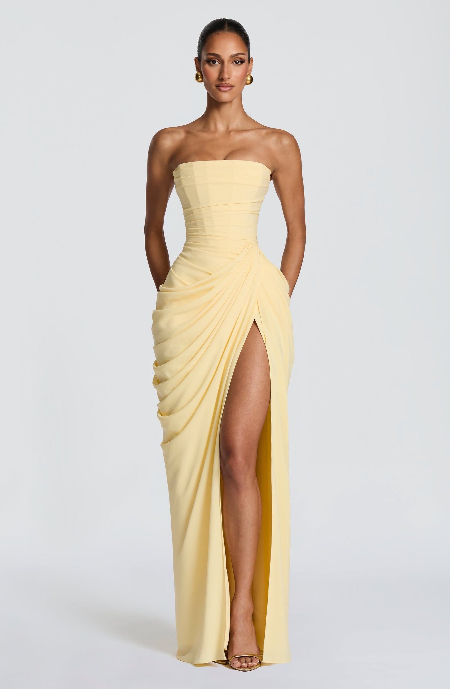 Pale yellow strapless draped bodycon maxi dress with ruched skirt and high thigh slit, front view