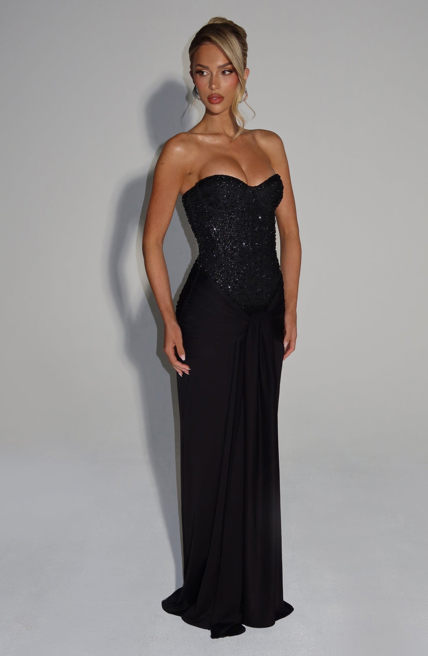 Full-length black formal strapless sequin corset maxi dress with draped waist detail and bodycon fit
