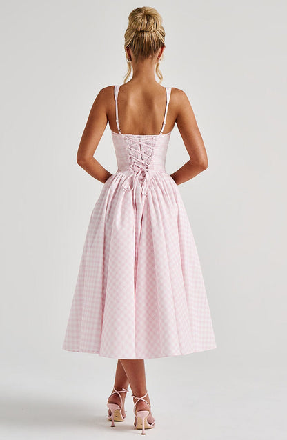 Back view of a light pink gingham square neck midi dress, showcasing the lace-up corset style back and full skirt.