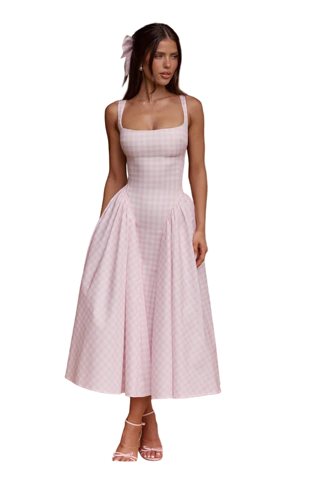 Woman in a light pink gingham square neck midi dress with a full pleated skirt and delicate pink bow heels, standing in a doorway.