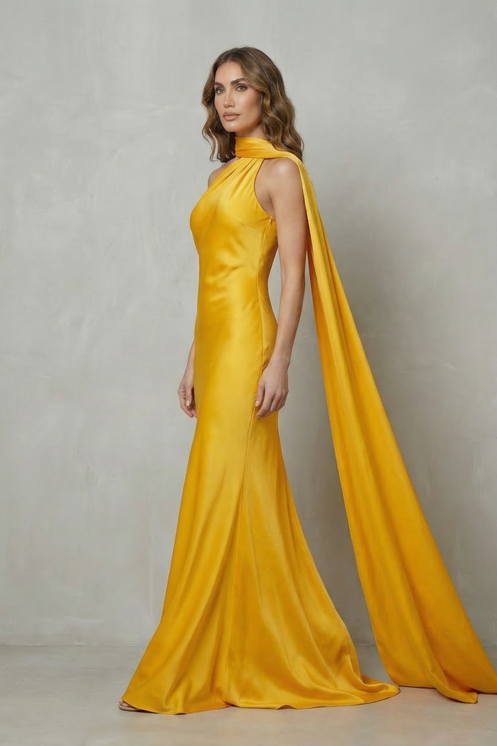 Side profile of a yellow formal halter draped open back maxi dress, showcasing the flowing train and elegant silhouette.