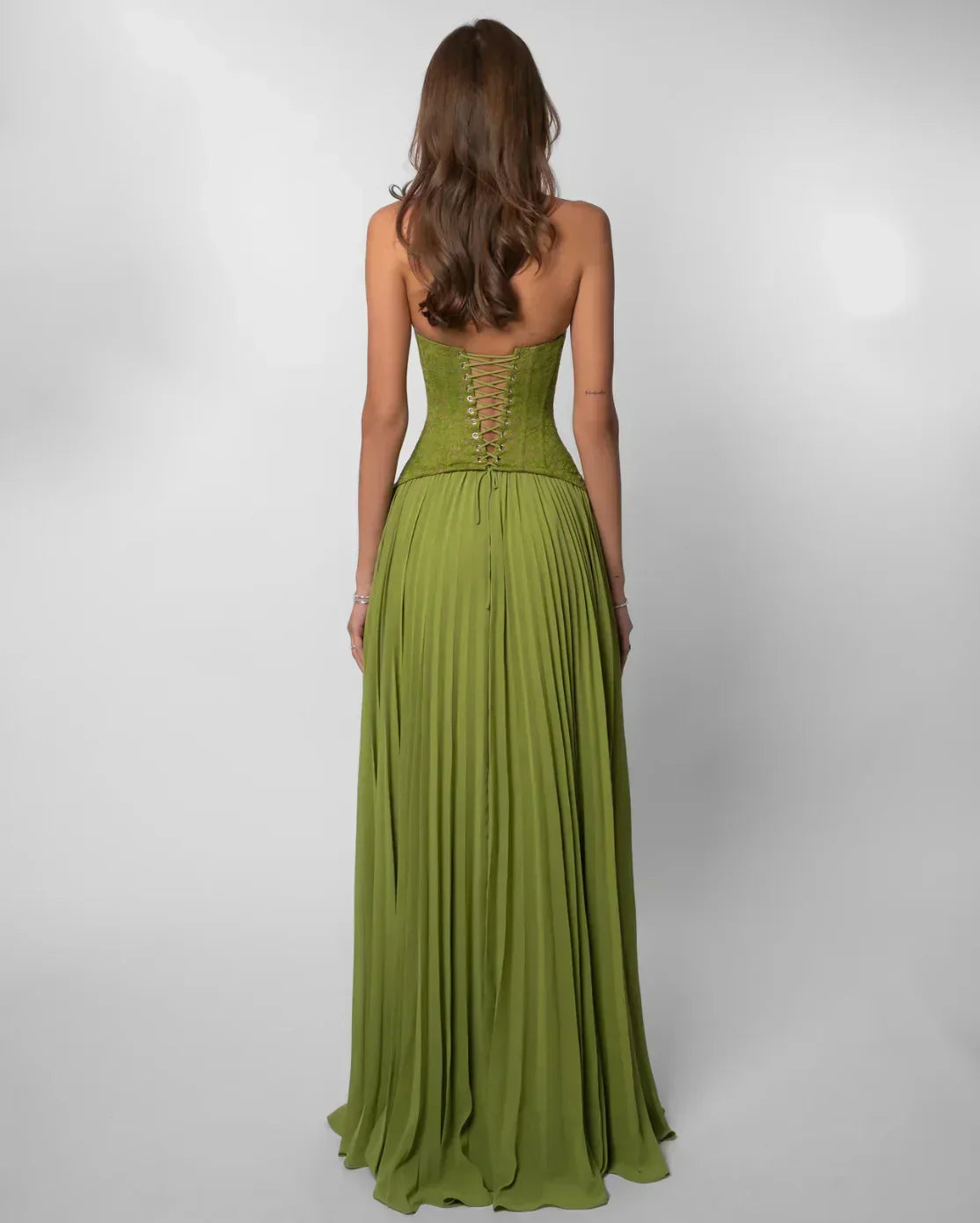 Back view of the olive green formal halter neck maxi dress, highlighting the lace-up corset back and flowing pleated skirt.