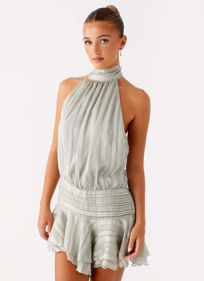 Close-up of the upper body of a light sage green halter neck mini dress, showing the high neckline and ruched bodice details.
