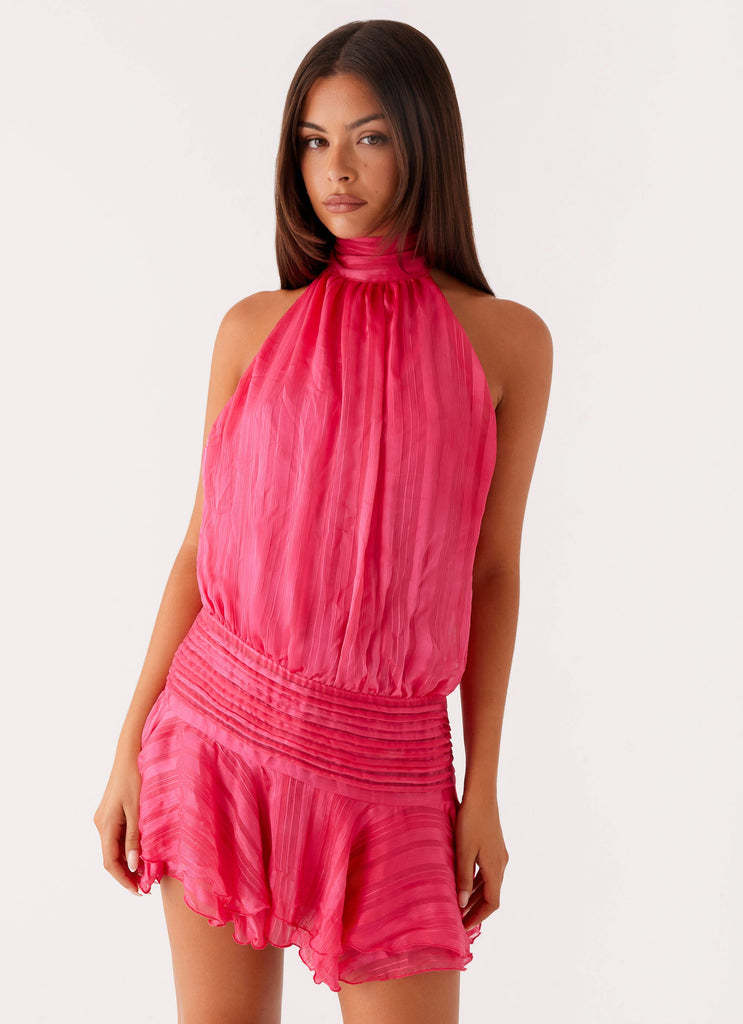 Vibrant hot pink halter neck mini dress with ruched waist and ruffled hem, shown on a model looking forward.