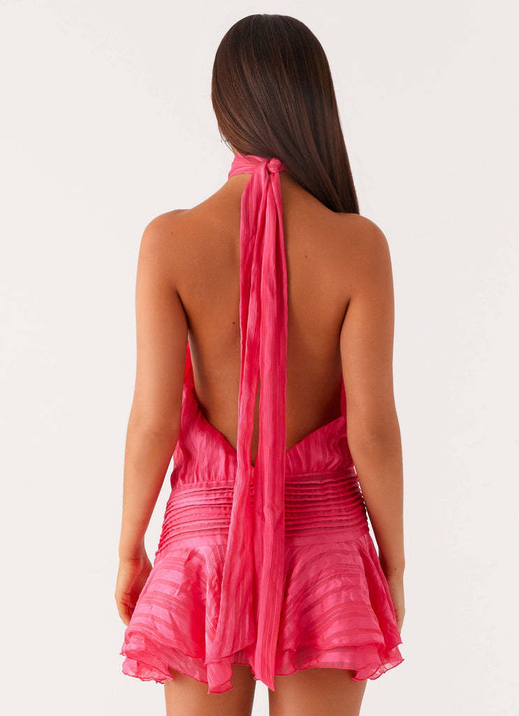 Back view of the hot pink halter neck mini dress, showing the deep open back and the long tie detail.