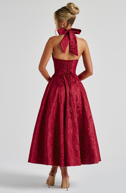 Back view of a red jacquard halter neck midi dress with a large bow detail and corset lacing on the back.