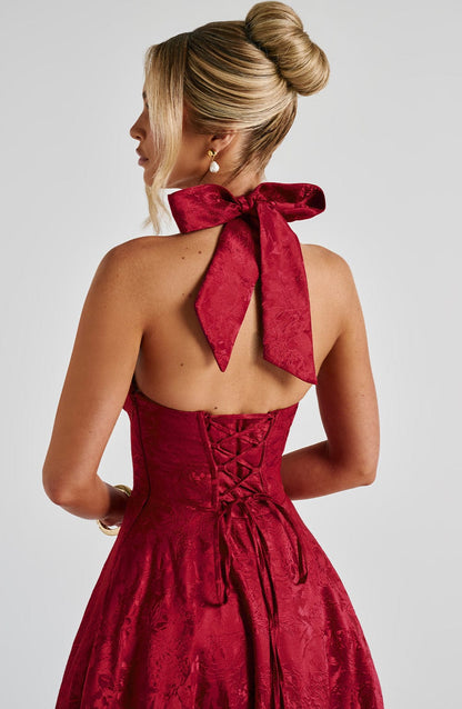 Rear view of a red jacquard halter neck midi dress showing the tied bow at the neck and lace-up corset back.