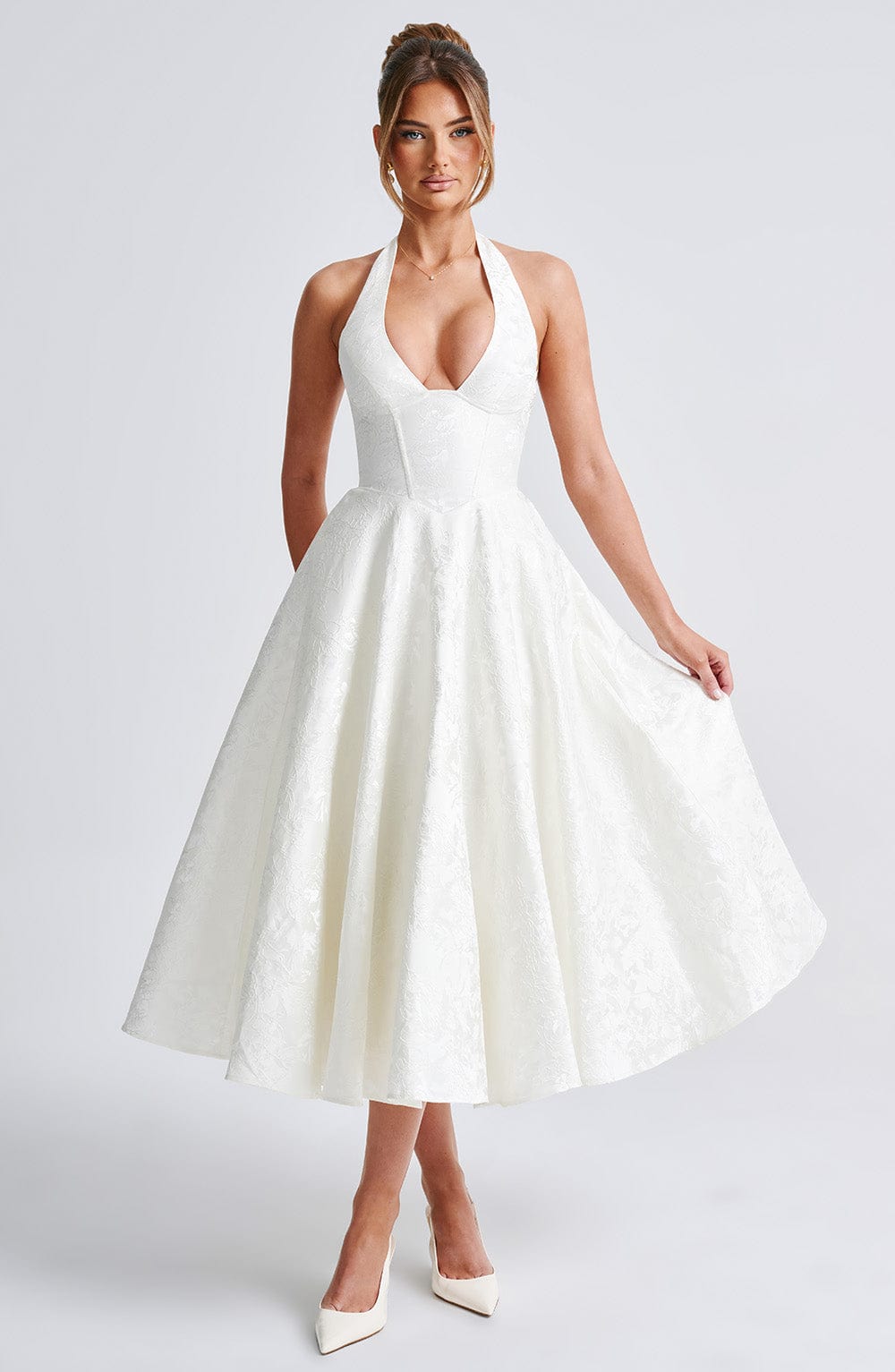 Full body front view of a white jacquard halter neck midi dress with a deep V-neck and flowing skirt.