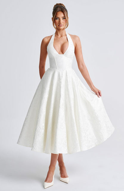 Full body front view of a white jacquard halter neck midi dress with a deep V-neck and flowing skirt.