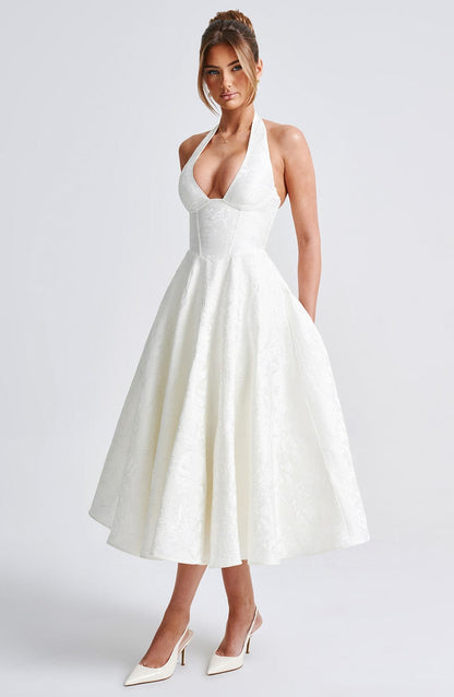 Side view of a white jacquard halter neck midi dress, highlighting the A-line skirt and textured fabric.