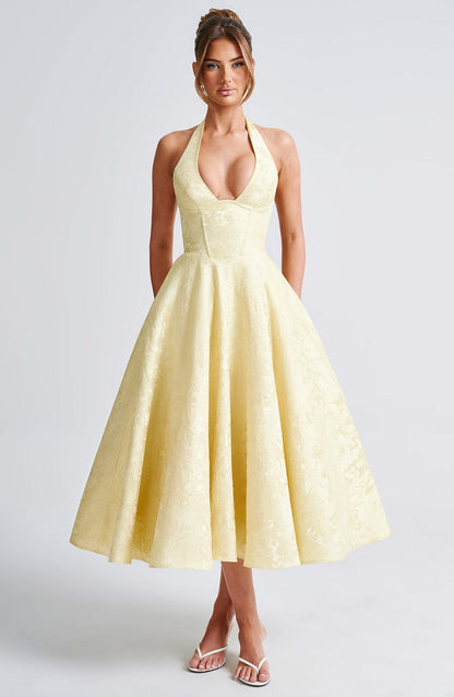 Soft yellow jacquard halter neck midi dress with a structured bodice and a full, mid-calf length skirt.