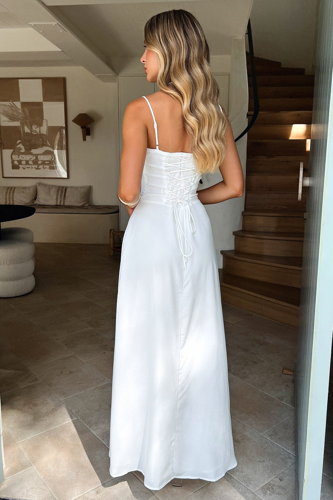 Back view of a woman in a white sleeveless maxi dress, showcasing the delicate lace-up back and the elegant silhouette, suitable for wedding guest dresses.