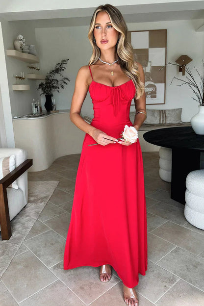 Front view of a woman in a vibrant red sleeveless maxi dress, featuring a lace-up bust detail and a full-length skirt, holding a rose.